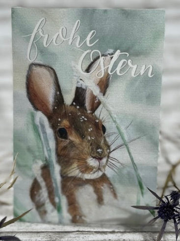 Aquarellgemälde eines Schneehasen mit braunem Fell, der von Grashalmen umgeben ist.